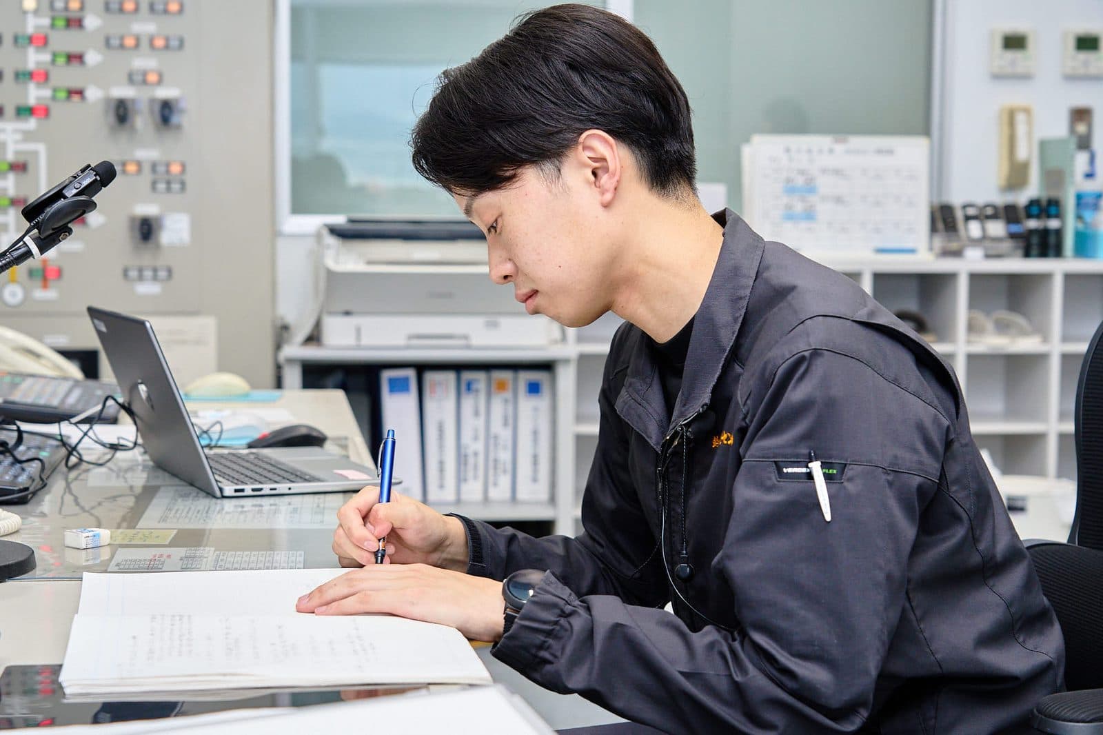 制御室で書き込み作業をする社員